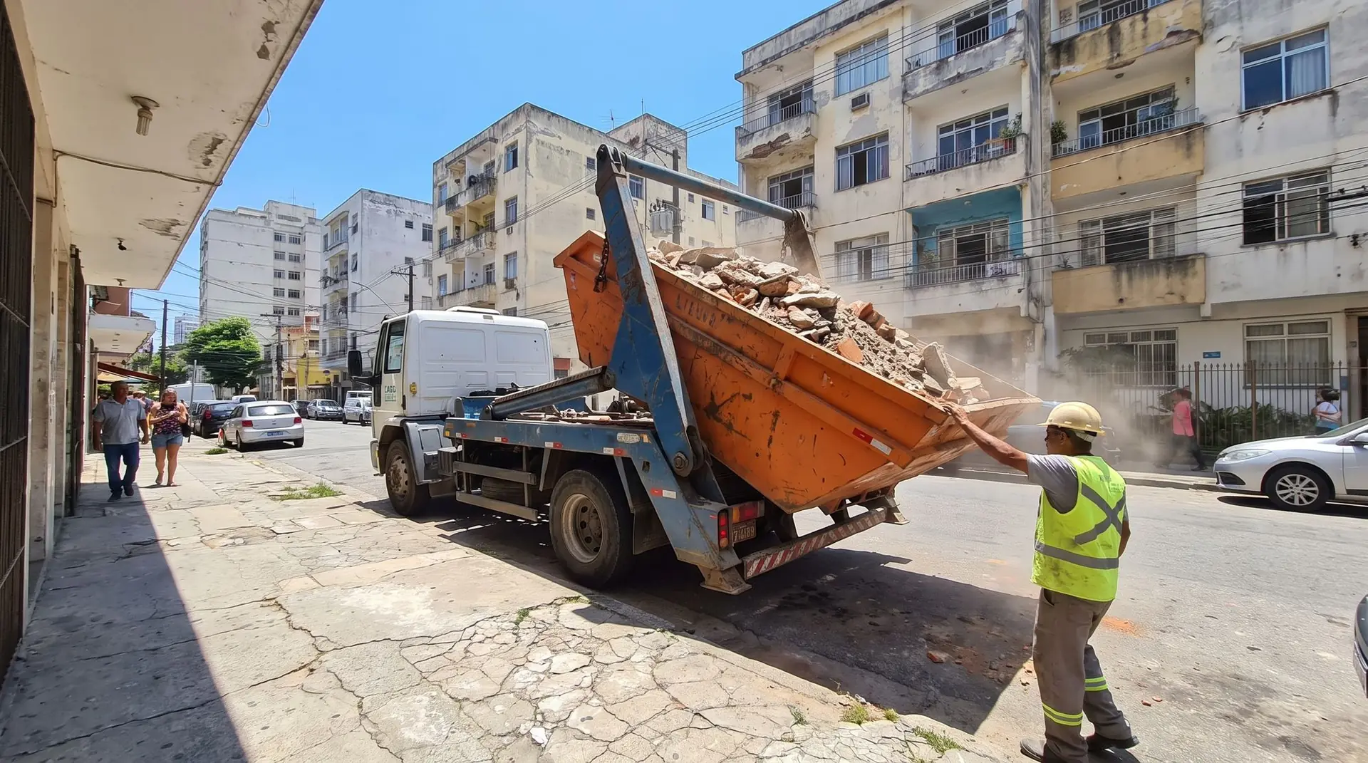 Caminhão poliguindaste içando uma caçamba cheia de entulho na rua